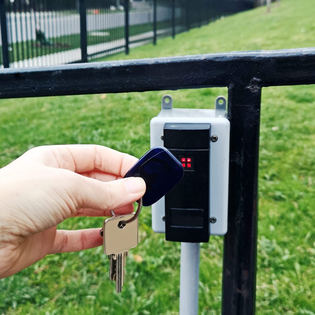A person holding attaching key fob to open door. Closeup of a human hand with magnetic key fob for allowing access. Secutity system mechanism technology. A person holding attaching key fob to open door. Closeup of human hand with magnetic key fob for allowing access. Secutity system mechanism technology.