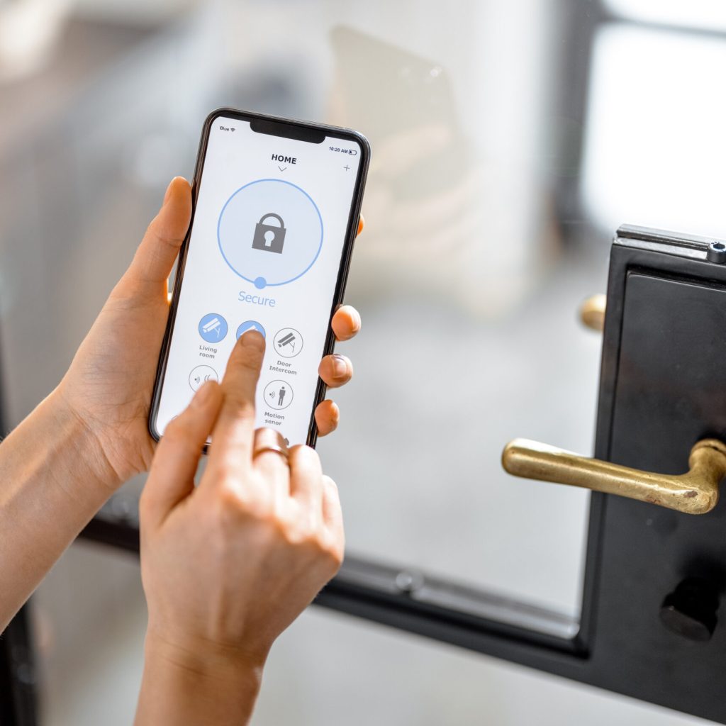 Smartphone with launched application for alarm security Smartphone with launched application for alarm security system, lock or unlock entrance door on interior background. Focus on mobile. Smart and safe home concept.
